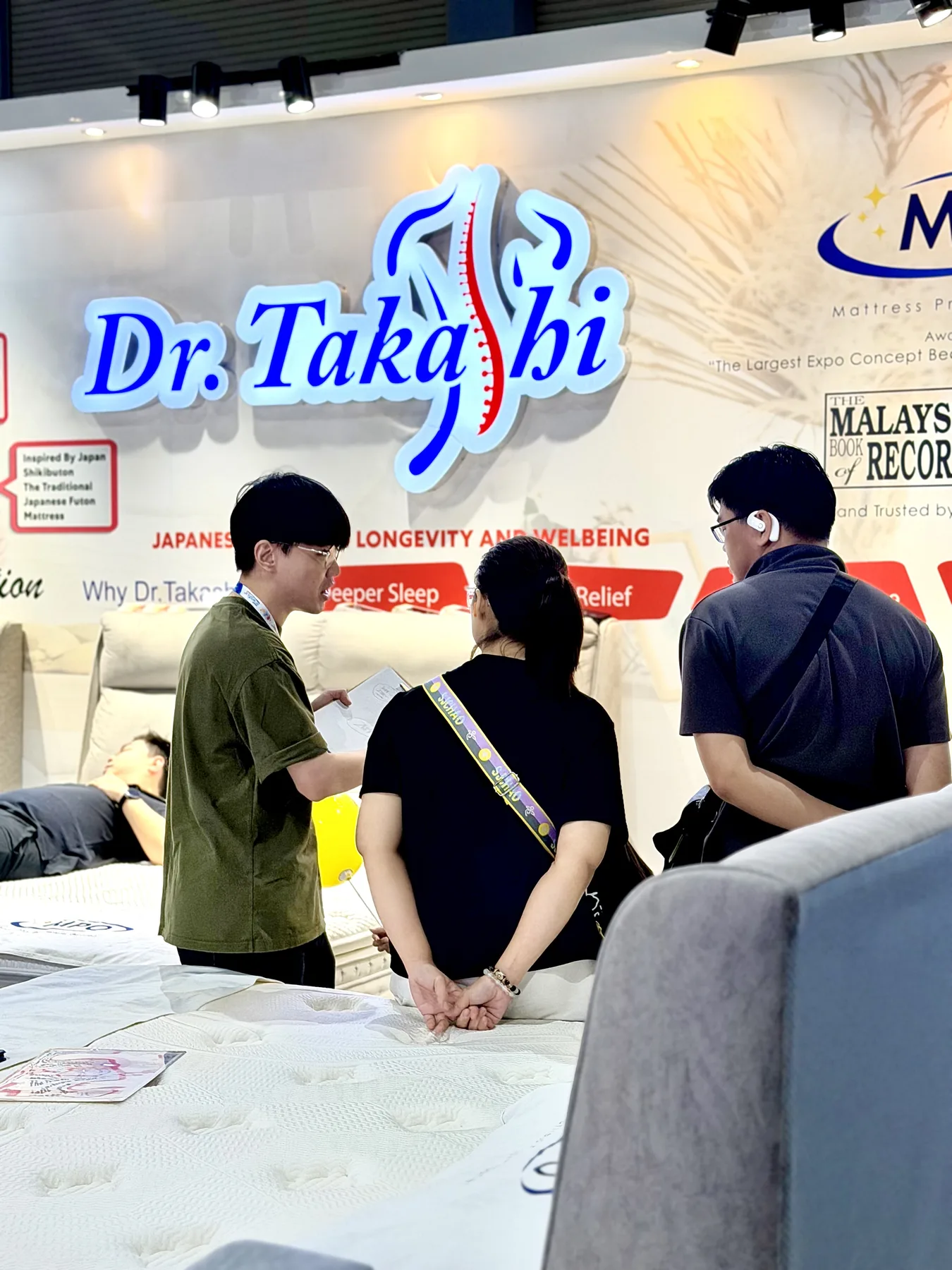 Visitors exploring Dr. Takashi mattresses at a home and living exhibition.