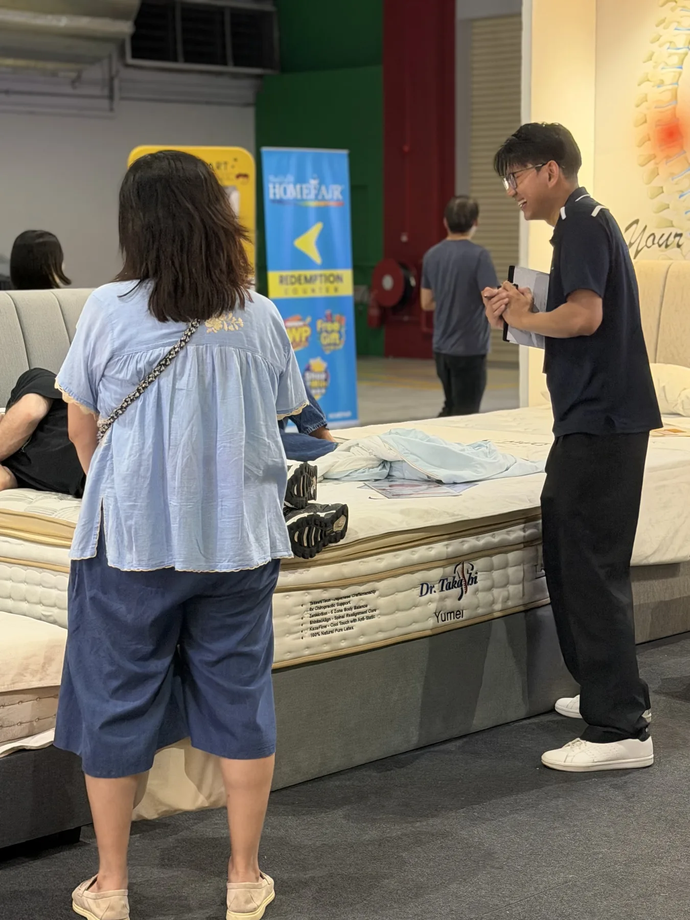 A visitor testing a Dr. Takashi mattress at a home exhibition.